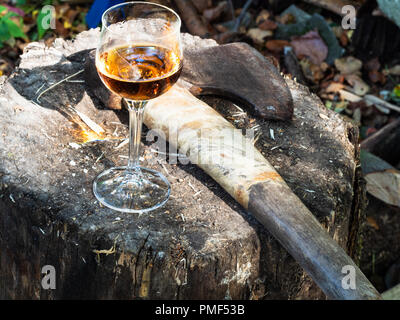 wine glass and ax on wooden block in country yard Stock Photo
