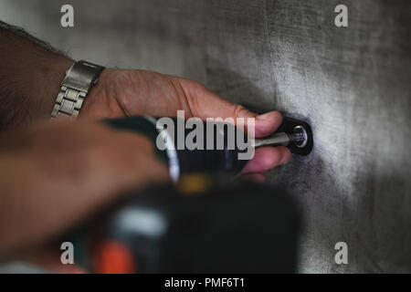 Close up shot of a man using a light-assisted power drill to put together some furniture. Stock Photo