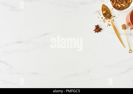 Flat lay of fresh black tea, with golden spoon, dipper and herbs on white marble background. Top view with copy space. Stock Photo