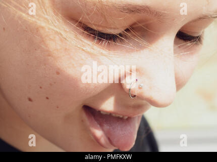 A young woman sticking her tongue out after getting a new nose ring. Stock Photo
