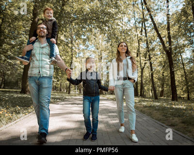 family with children walking along the path in the city Park Stock Photo