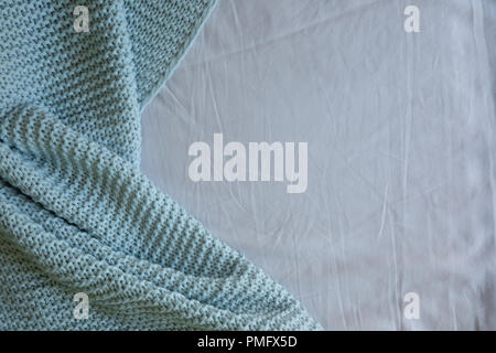 Handmade blue knitted wool blanket on bed, texture background Stock Photo