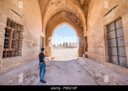 Unidentified boy stands in front of Han El Ba'rur,a Seljuk caravanserai in Harran,Sanliurfa,Turkey. Stock Photo