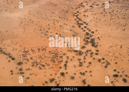 A top-down, aerial view of a traditional circular village of huts and animal enclosures next to a dry river bed in the arid Kaisut desert near Marsabi Stock Photo