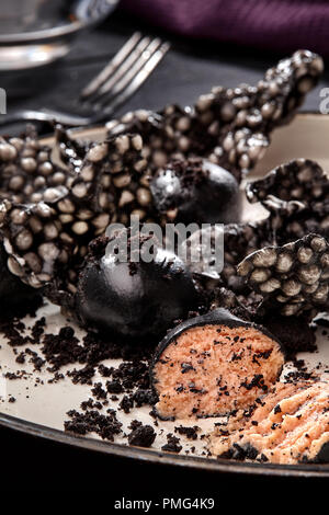 Appetizer with salmon pate, ink cuttlefish, crackers served on white tray over black wooden background. Close-up. Photo for the menu. Molecular gastro Stock Photo