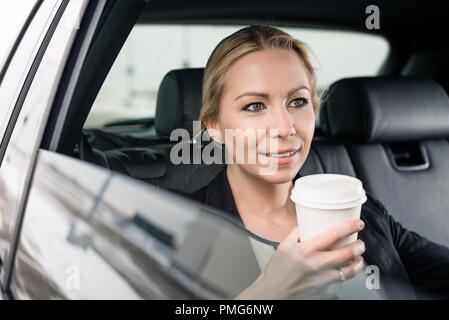 Businesswoman holding coffee cup sitting in the car Stock Photo