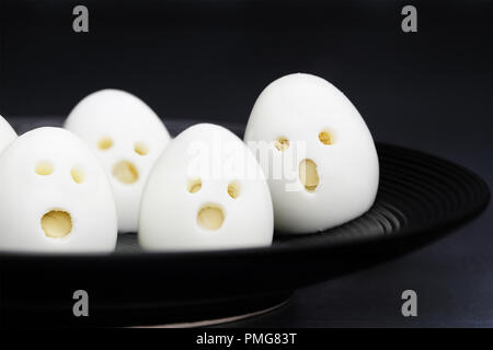 Fun food for kids. Hard boiled ghost ghool eggs perfect for Halloween parties. Alternative to candy. Shallow depth of field with selective focus on eg Stock Photo