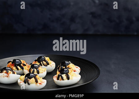 Fun food for kids. Halloween boiled eggs with black olive spiders on top of them. Alternative to candy. Stock Photo