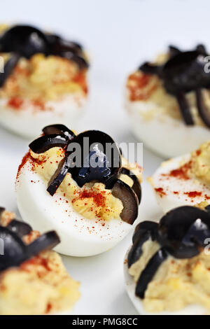Fun food for kids. Halloween boiled eggs with black olive spiders on top of them. Extreme shallow depth of field with selective focus on center egg. A Stock Photo