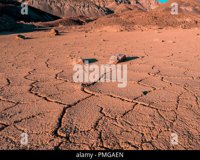 Dried up lakebed in the middle of a desert with colorfull mountains in the background Stock Photo