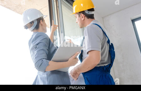 Architect and construction worker checking windows on site Stock Photo
