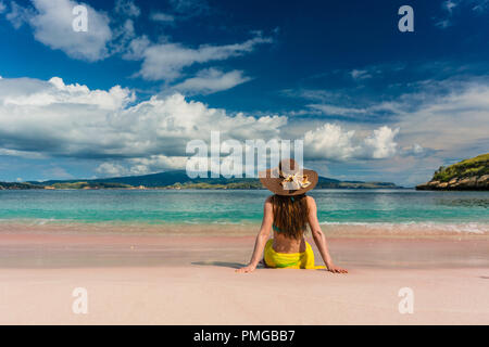 Young woman sitting on the sand at Pink Beach in Komodo Island Stock Photo