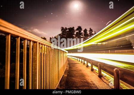 Long exposure shot of the Schiffenen Dam, in the County of Fribourg in Switzerland, with vehicle light trails on the side Stock Photo