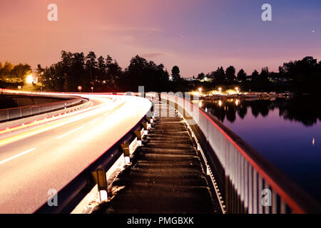 Long exposure shot of the Schiffenen Dam, in the County of Fribourg in Switzerland, with vehicle light trails on the side Stock Photo