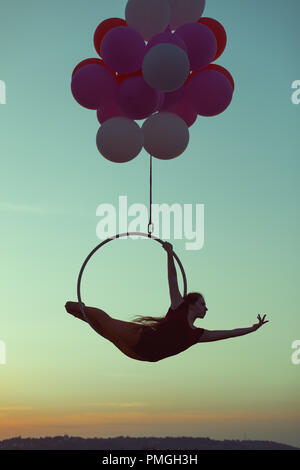 A young girl performs the acrobatic elements in the air trapeze