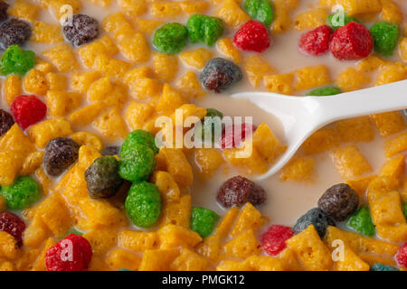 Close view of generic fruit flavored breakfast cereal with milk and a white plastic spoon. Stock Photo