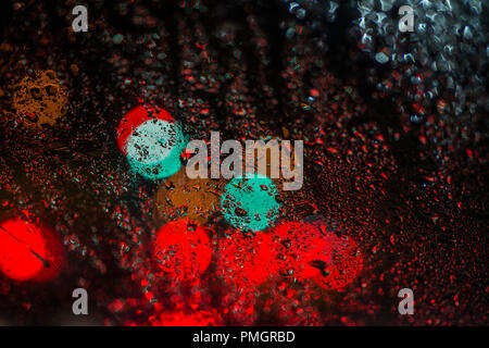 colored lights of cars and traffic lights through the windshield with raindrops Stock Photo