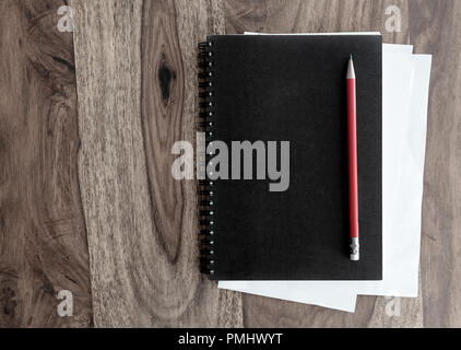 black spiral notebook and pen on wooden table Stock Photo