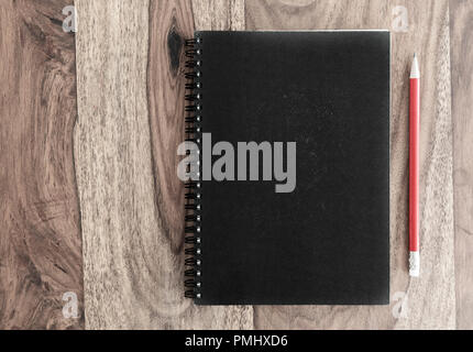 closed black spiral notebook and pencil on wooden desk Stock Photo