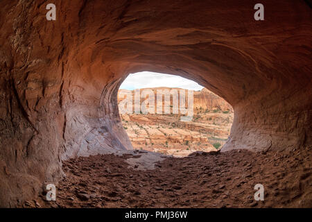 The view looking out of a cave high above the trail to Corona Arch, Moab, Utah, USA Stock Photo