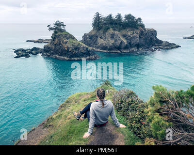Woman sitting on cliff looking at view, Samuel H Boardman State Park, Oregon, United States Stock Photo