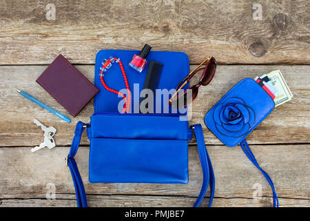 Things from open lady purse. Cosmetics, money and women's accessories fell out of blue handbag. Top view. Stock Photo