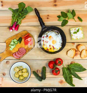 Different food: scrambled eggs in frying pan, boiled potatoes, curd, croutons, radishes, cucumbers, tomatoes, smoked sausage, croutons, mint, sorrel o Stock Photo