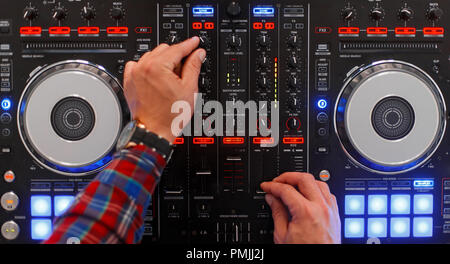 DJ in the process of work. Men's hands are played on the mixing console. Top view Stock Photo