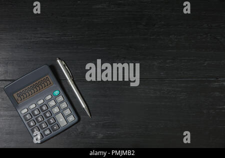 A calculator and pen on wooden background with copy space for insert text. Stock Photo