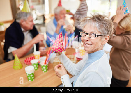 Old woman and seniors friends celebrate birthday party together at retirement home Stock Photo