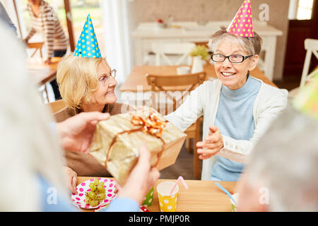 Senior woman as a birthday girl is happy about a gift at her birthday party Stock Photo