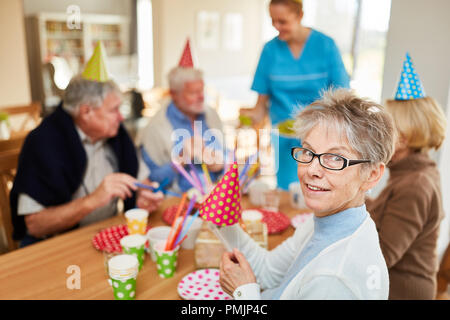 Happy seniors at a birthday party in retirement home at the coffee table Stock Photo