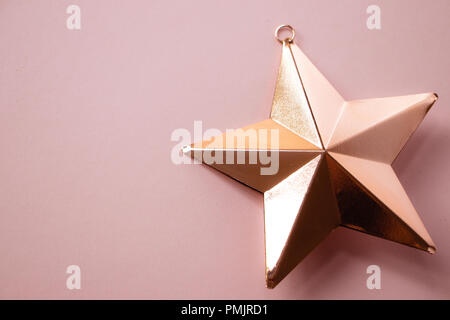 Rose gold Shiny Christmas Star Bauble on Pink Background Stock Photo