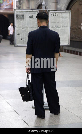 Korean citizen reading the daily newspaper which is on public display at a metro station Stock Photo