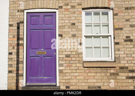 Violet pastel vintage front door on a restored brick wall of a Georgian house residential building with white wooden sash window Stock Photo