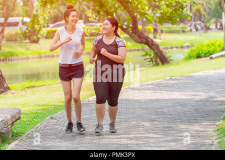 Asian two thin and fat girls friend running jogging park outdoor in the morning Stock Photo