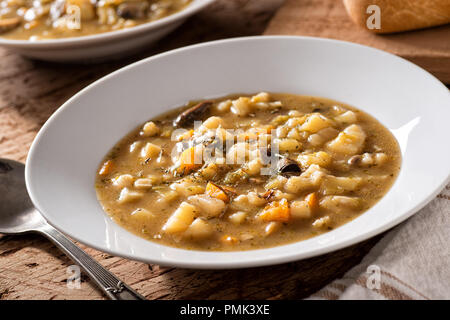 A bowl of delicious wild mushroom and potato soup with root vegetables. Stock Photo