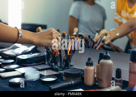 Makeup artist picking up a brush for working on a model. Close up of hand of makeup artist picking up a makeup brush. Stock Photo