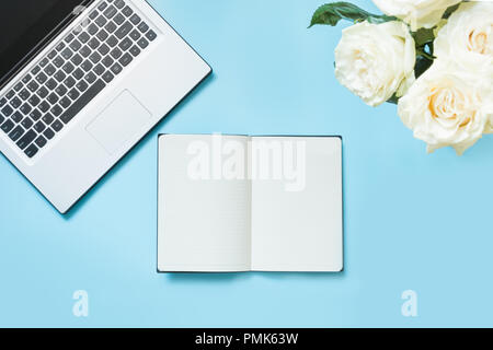 Female desktop with a open laptop and flowers on vintage background. Top view composition with copy space. Stock Photo