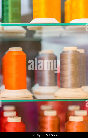 Background with a lot of colorful coils with threads. Bobbins are stacked in three rows, one on the other. The winding is erratic. Multicolored thread Stock Photo