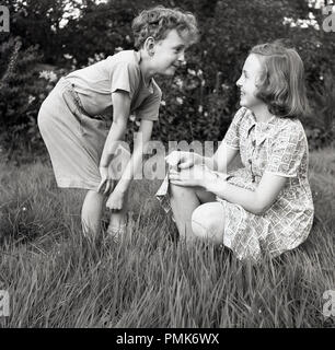 https://l450v.alamy.com/450v/pmk6wx/1950s-historical-children-playig-keep-a-straight-face-outside-in-the-grass-big-sister-laughing-at-her-younger-brothers-funny-face-england-uk-pmk6wx.jpg