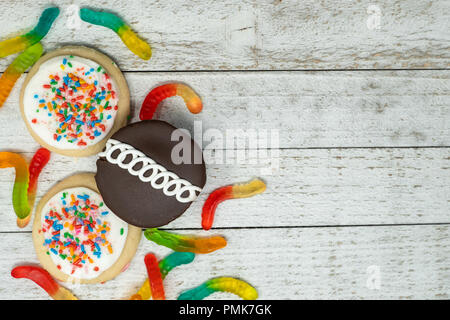 Chocolate cupcake, iced frosted sugar cookies with sprinkles and gummy worms on wooden background Stock Photo