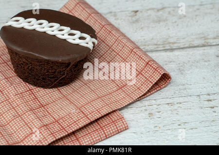 Chocolate swirled decorated cupcake with red napkin on wood background Stock Photo