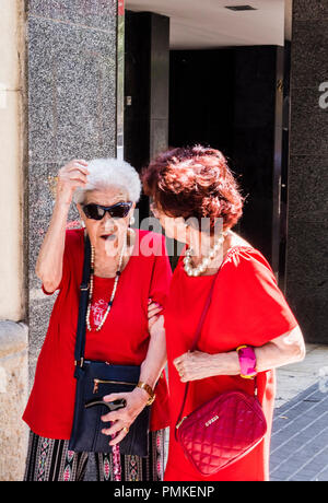 Two senior women, wearing bright red clothes, walking through the city, Barcelona, Spain, Europe Stock Photo