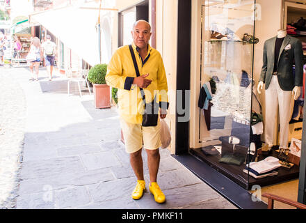 Portrait of man wearing yellow clothes, standing beside clothes shop, Portafina, Genoa, Italy, Europe Stock Photo
