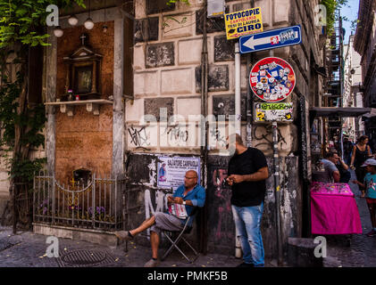 Two men relaxing on street corner, in an old area of Naples, Italy, Europe Stock Photo