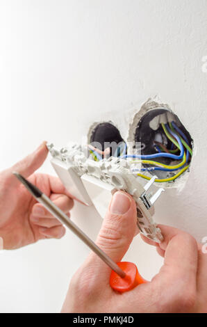 Closeup of handyman's hands while installing a light switch. Stock Photo