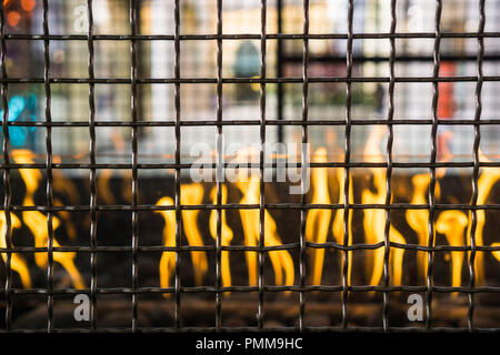 Metal grid enclosing an outdoors fire used for getting warm in an open air shopping center Stock Photo