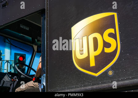 April 19, 2018 Santa Clara / CA / USA - Close up of UPS logo printed on a delivery truck; driver sitting at the wheel, waiting at a red traffic light Stock Photo