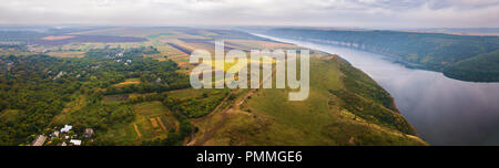 Panorama of big river canyon, village and rural fields on hills. Aerial view on green and yellow parts of fields in autumn season. River Dniester, Pod Stock Photo